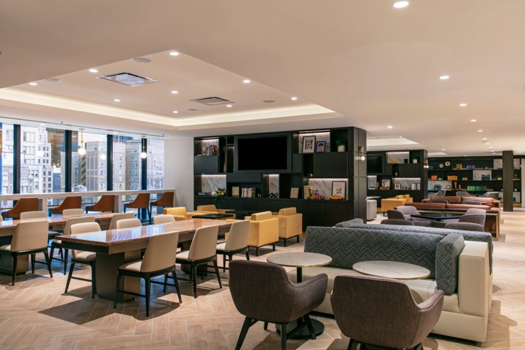 Spacious lounge at the New York Marriott Marquis featuring modern furnishings, large windows overlooking the city, and a cozy seating area, ideal for guests visiting for the US Open Tennis.