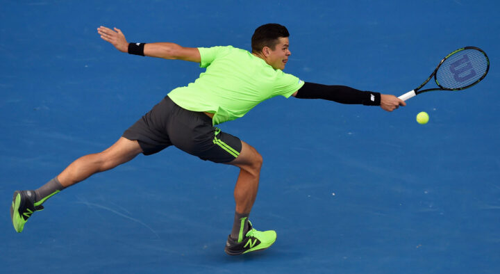 Male tennis player in a neon green shirt stretches to hit a ball during a match at Melbourne Park, part of the Australian Open Tennis Schedule.