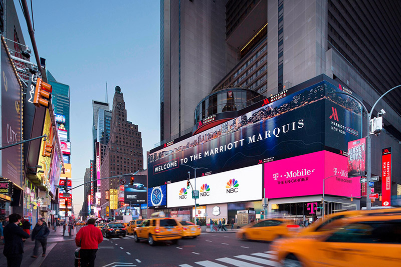 View of the New York Marriott Marquis in Times Square, featuring bustling street activity and brightly-lit digital billboards.