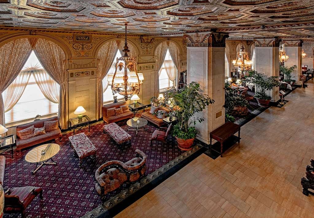 Luxury hotel lobby in Louisville, Kentucky, decorated with plush seating, ornate chandeliers, and large drapes, ideal for Kentucky Derby accommodations near Churchill Downs.