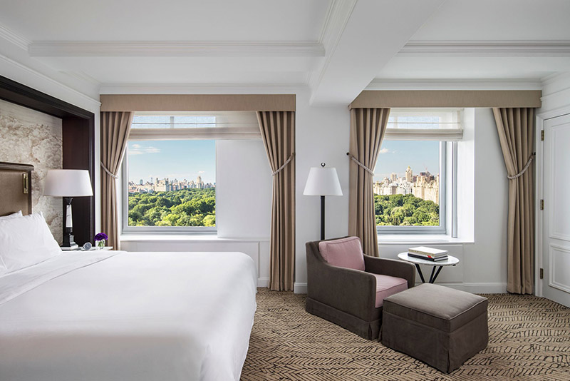 Luxurious hotel room at the Ritz-Carlton Central Park, featuring a large bed, elegant furniture, and a stunning view of Central Park, ideal for guests attending the US Open Tennis in New York.