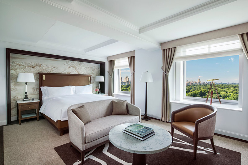 Luxury hotel room at the Ritz-Carlton Central Park, featuring a large bed, sitting area, and a view of Central Park, ideal for visitors to the US Open Tennis in New York.