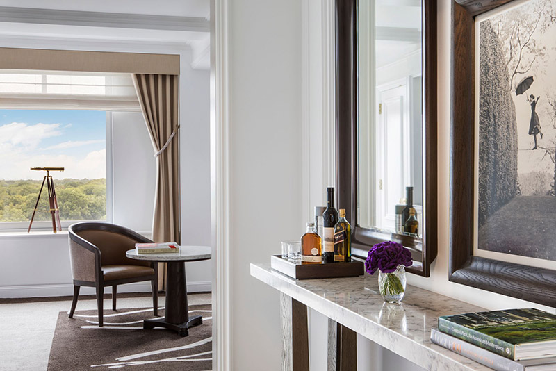 Luxury hotel suite interior at Ritz-Carlton Central Park, showing a window with park views, an elegant chair, table setup, and decorative elements ideal for US Open Tennis attendees.