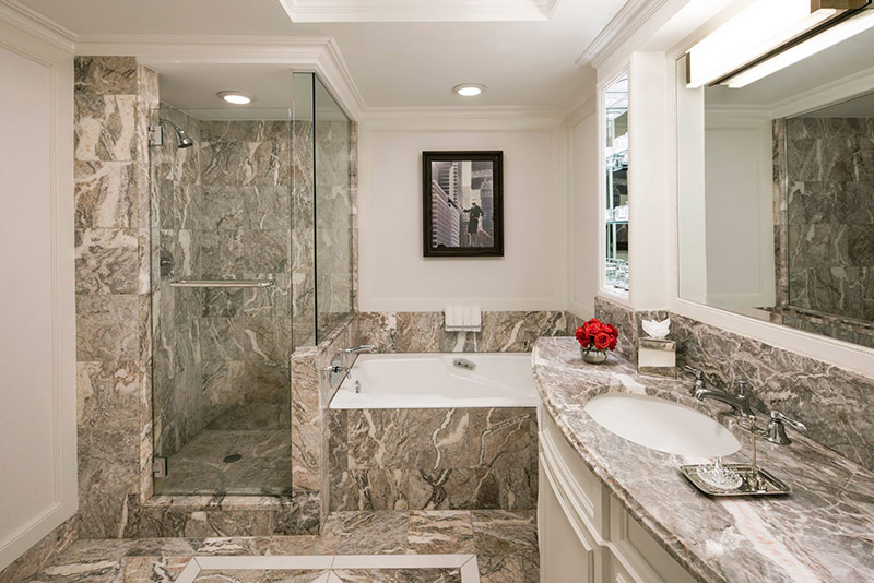 Elegant marble bathroom at the Ritz-Carlton Central Park, featuring a bathtub, walk-in shower, and large mirror, ideal for guests attending the US Open Tennis in New York.