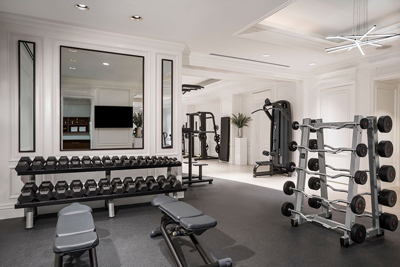 Well-equipped gym at the Ritz-Carlton Central Park featuring weights, resistance machines, and large mirrors, ideal for guests attending the US Open Tennis in New York.