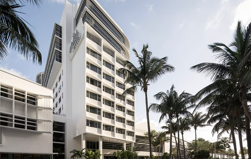 Exterior view of the Ritz-Carlton South Beach, a luxury hotel flanked by palm trees under a clear sky, relevant for travelers considering Club World Cup packages in Miami.