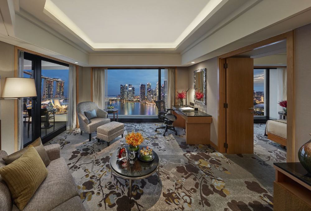Luxurious hotel suite in Singapore with a stunning view of the Marina Bay, featuring elegant decor and a comfortable seating area, ideal for visitors attending the Singapore Grand Prix.