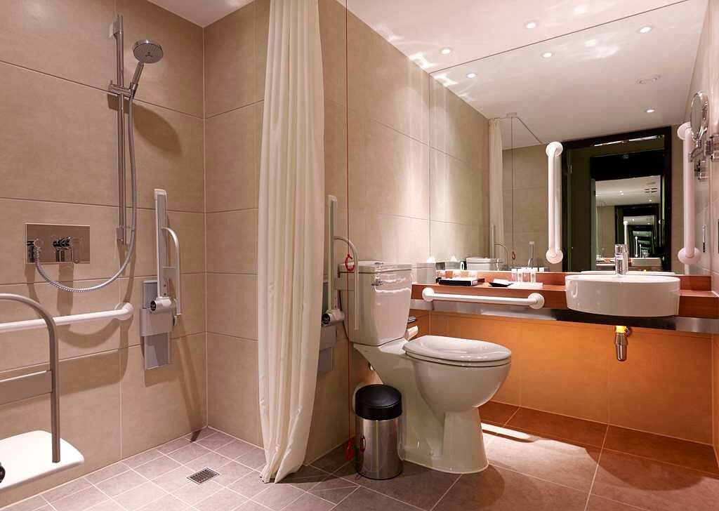 Accessible bathroom with grab bars, a walk-in shower, and double sinks in a luxury hotel near Westminster Bridge, ideal for visitors attending Wimbledon in London, England.