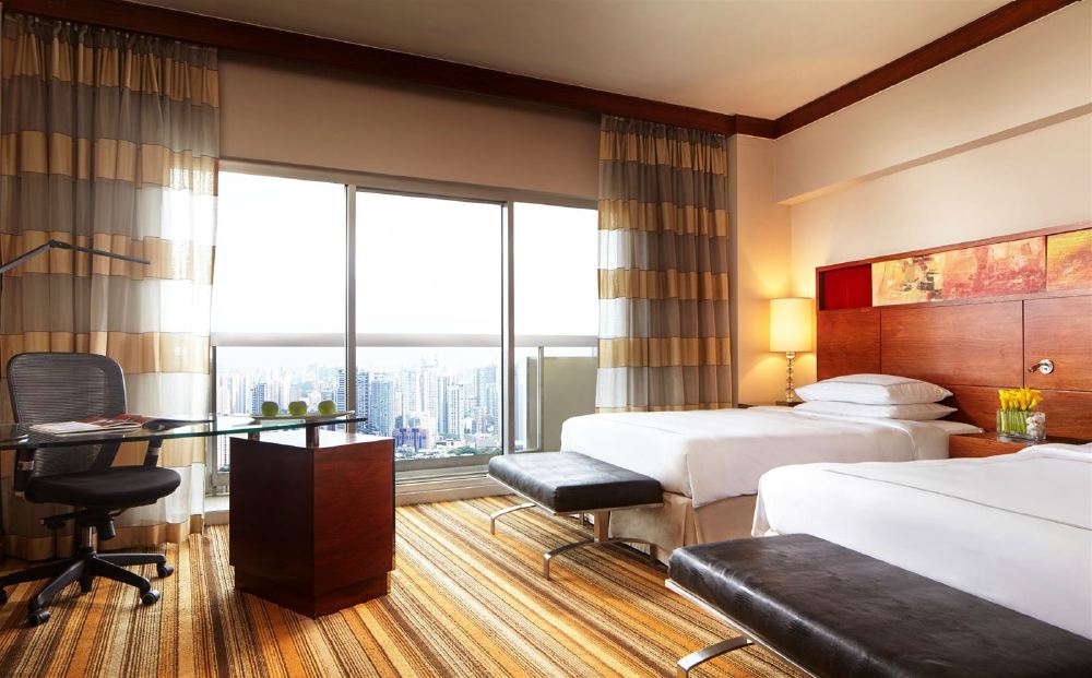 Luxurious hotel room at Swissotel The Stamford in Singapore, featuring modern furnishings and a large window overlooking the city skyline, ideal for guests visiting the Singapore Grand Prix.