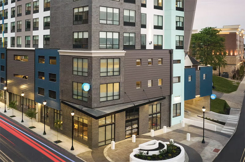 Exterior view of Tru by Hilton Indianapolis Downtown at 601 Russell Avenue, featuring modern architecture and distinctive blue branding near the Indianapolis Area Map.
