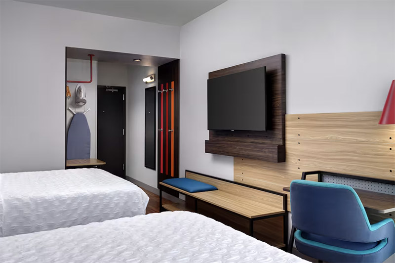 Modern hotel room featuring two beds, a television mounted on a wooden panel, and a sleek design perfect for guests attending the Indianapolis 500, located at Tru by Hilton Indianapolis Downtown.