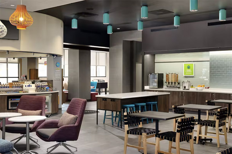 Modern hotel lounge and dining area at Tru by Hilton Indianapolis Downtown, featuring stylish seating and a breakfast bar, ideal for guests visiting Indianapolis for the Indy 500.