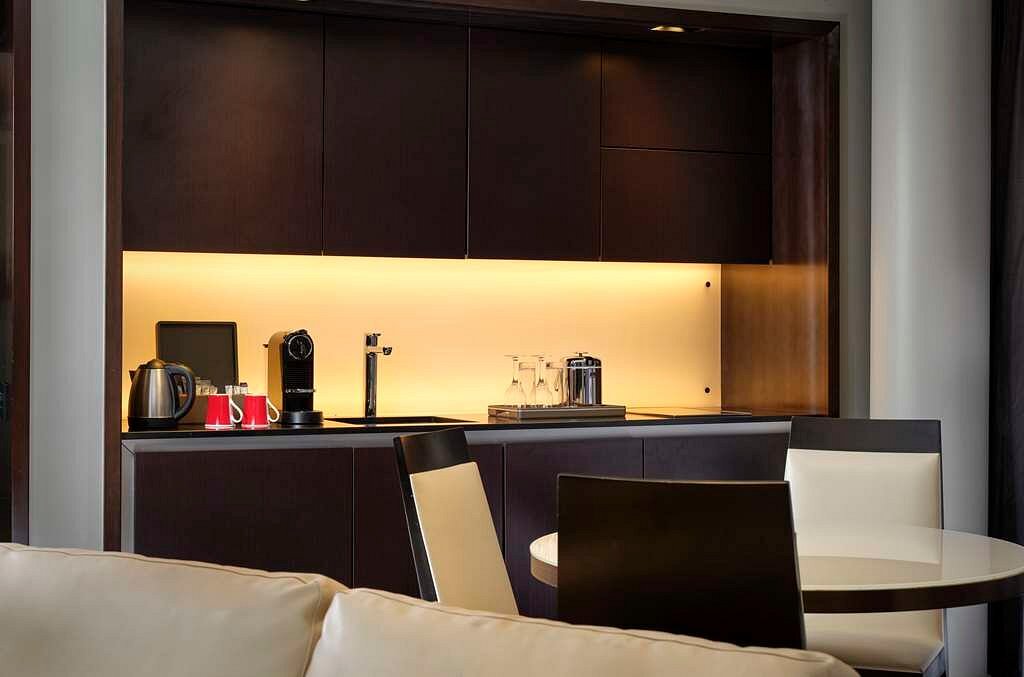 Luxury hotel suite in London featuring a modern kitchenette with a coffee machine and stylish furnishings, ideal for guests attending Wimbledon Championships.