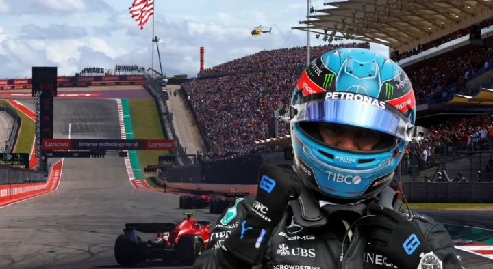 A racing driver in a blue helmet gestures a thumbs-up at the Circuit of the Americas in Austin, packed with spectators for a Grand Prix auto racing event.