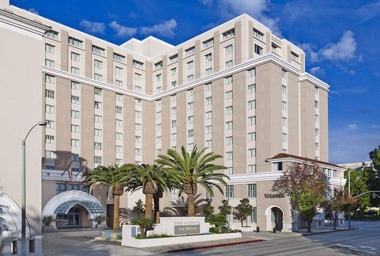 Exterior view of the Westin Pasadena, a luxury hotel located at 191 North Los Robles Avenue Pasadena, CA, surrounded by palm trees under a clear sky, ideal for Rose Bowl accommodations.