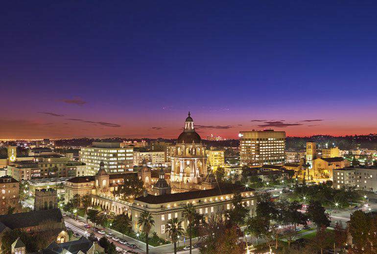 Twilight view of the illuminated cityscape of Pasadena, California, featuring prominent historic architecture.