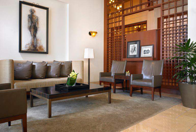 Elegant lobby in a Pasadena hotel, featuring modern furniture, decorative screens, and artwork, perfect for guests seeking luxury accommodations near the Rose Bowl.