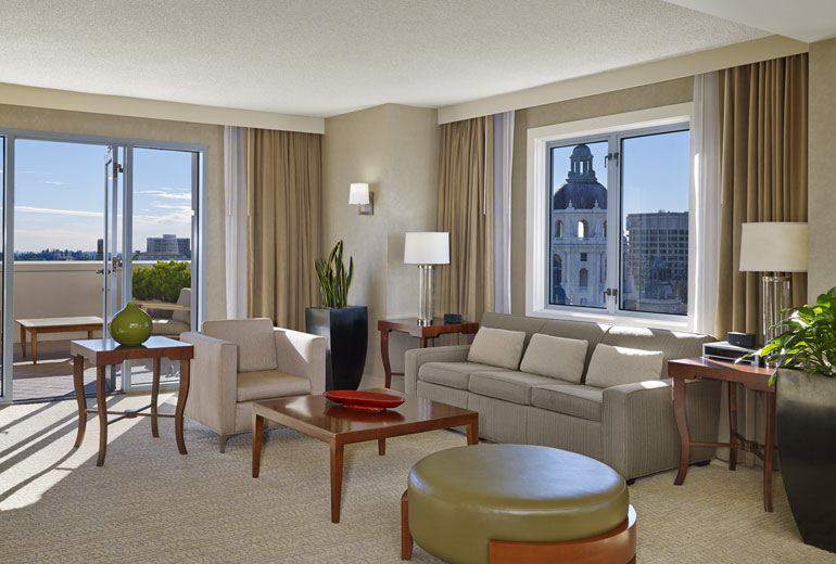 Spacious hotel room at the Westin Pasadena featuring elegant furniture, large windows with city views, ideal for guests attending the Rose Bowl event in Pasadena, California.