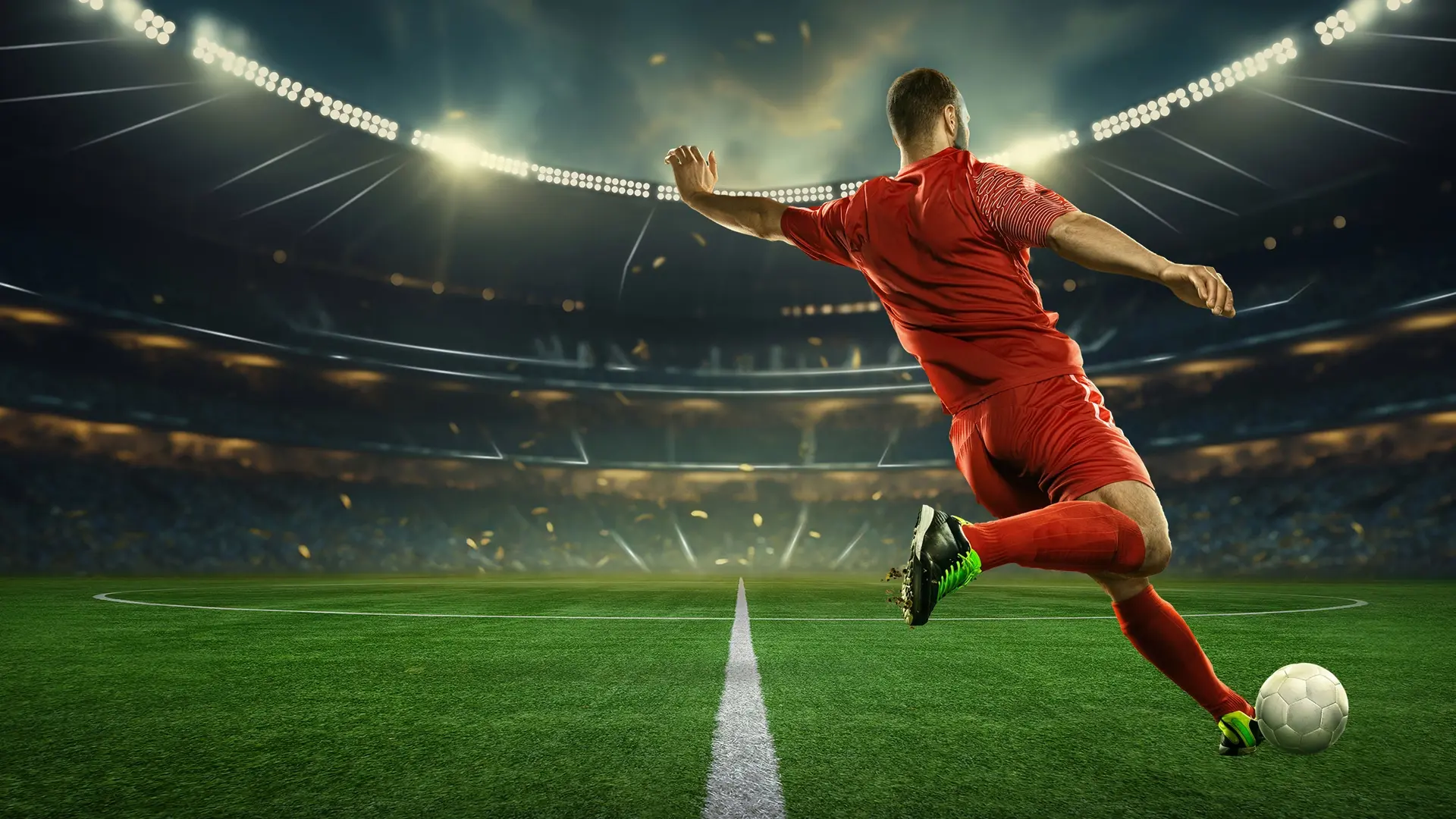 A soccer player in a red uniform kicks a ball on a brightly-lit stadium pitch, promoting sports travel packages by Roadtrips, a leader in luxury sports travel.
