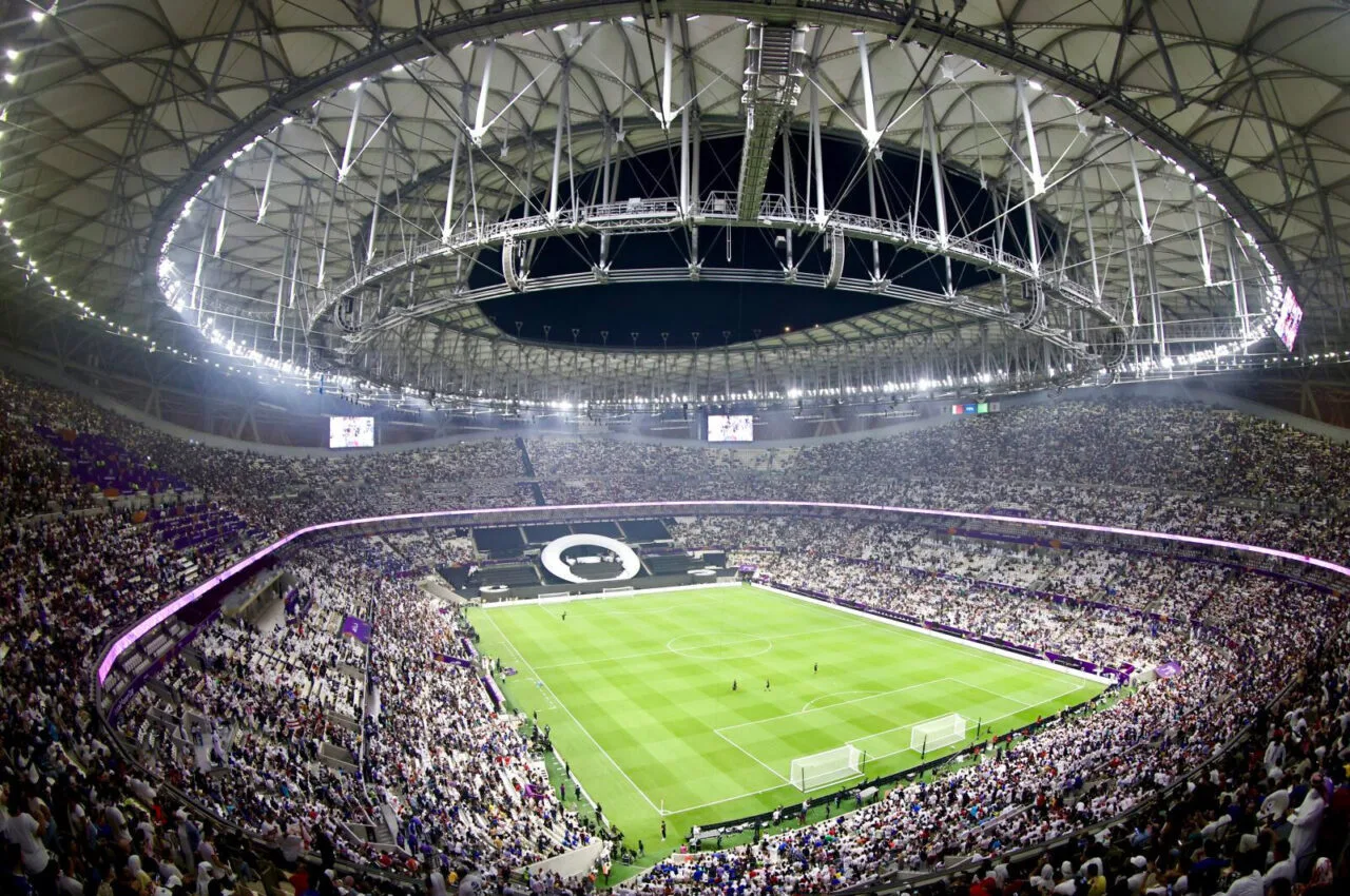 Wide-angle view of a packed stadium during a World Cup soccer match, featuring a large crowd and a closed retractable roof, in USA, Mexico, or Canada.