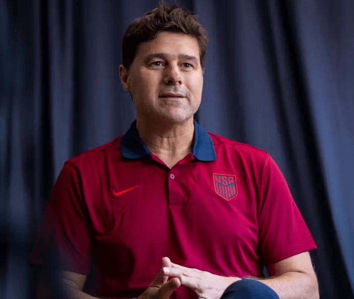 A man in a USA team polo shirt looks off-camera, symbolizing support for following Team USA in international football events.