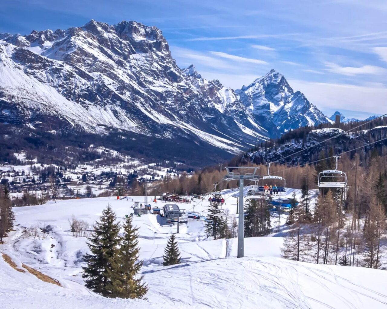 Snow-covered slopes and chairlifts with a mountain backdrop showcase a Winter Games venue in Milan and Cortina.