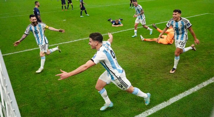 Soccer players in light blue and white stripes celebrate a goal during a match, with opponents in dark uniforms on the ground, capturing the excitement of World Cup Finals Packages.