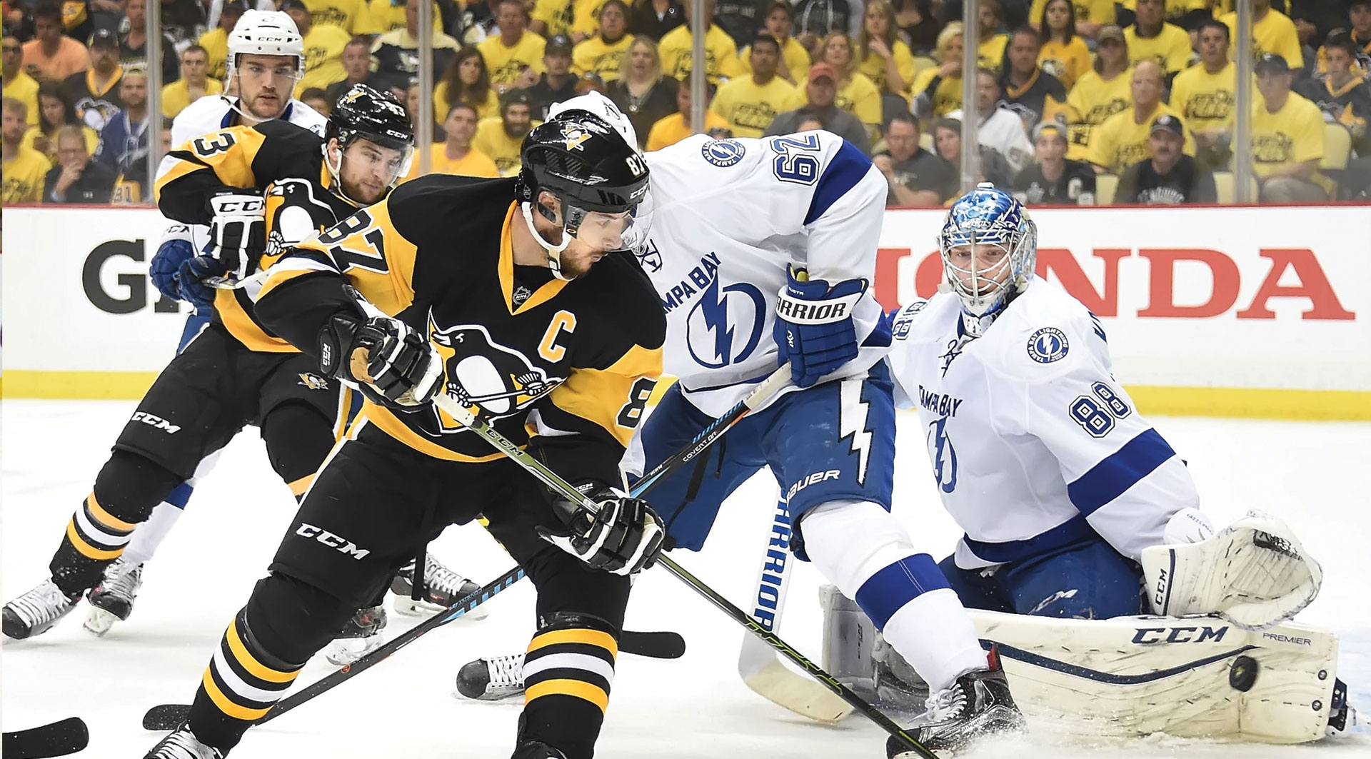 Hockey players in a tense game moment, with one attempting a goal past the goaltender, illustrating the dynamic action ideal for hockey travel packages including hotel and ticket packages.