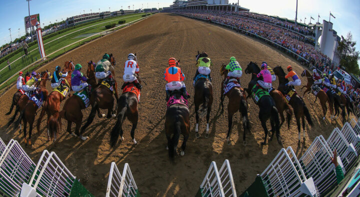 Horse racing event in full swing with jockeys on horses in colorful attire, racing on a dirt track in front of a packed grandstand, perfect for horse racing travel packages.