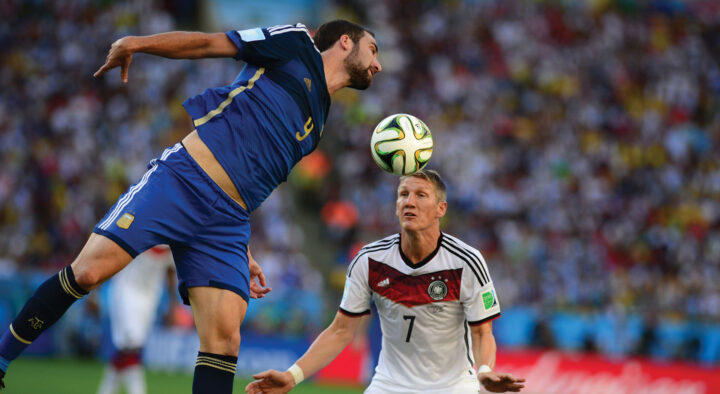 Two soccer players from opposing teams actively competing for the ball during a match, illustrating the exciting experiences offered by custom soccer travel packages.