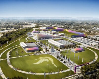 Aerial view of a spacious, colorful event venue in Los Angeles, bustling with visitors, set up for the Summer Games, featuring various tents and banners promoting the event.