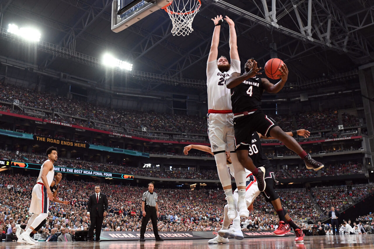 Two basketball players from South Carolina and Gonzaga vie for the ball during a high-stakes NCAA Final Four game, creating an unforgettable travel and game experience for fans.