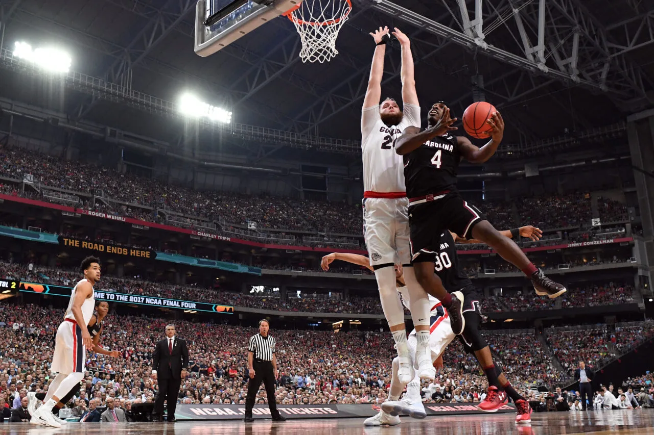 Two basketball players from South Carolina and Gonzaga vie for the ball during a high-stakes NCAA Final Four game, creating an unforgettable travel and game experience for fans.