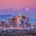 Downtown Los Angeles skyline during sunset with illuminated buildings and distant mountains, providing a backdrop for the Summer Games Los Angeles Area Map.