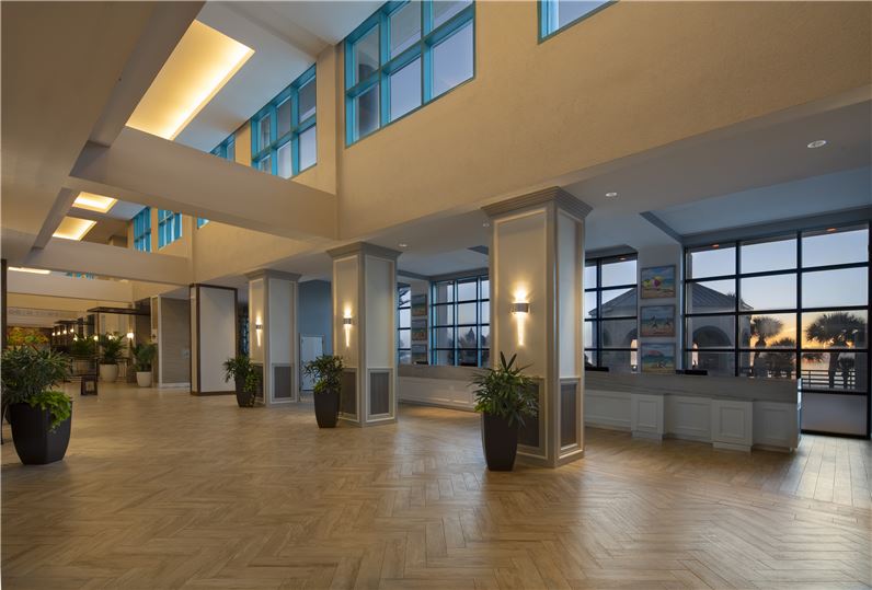 Interior of the Hilton Daytona Beach Oceanfront Resort showcasing a spacious lobby with modern lighting, large windows, and potted plants, ideal for guests visiting Daytona Beach hotels for events.