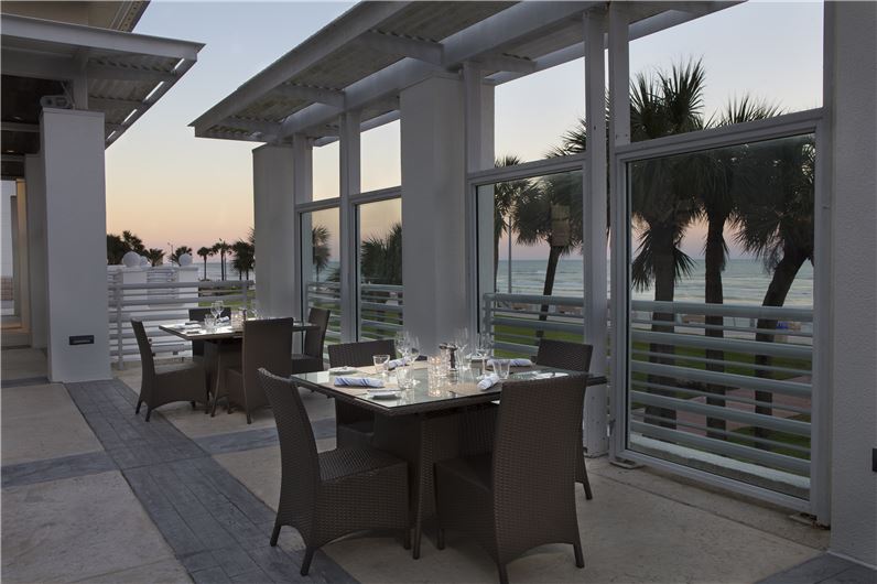 Outdoor dining setup at Hilton Daytona Beach Oceanfront Resort, featuring set tables and ocean views, ideal for guests visiting during the Daytona 500.