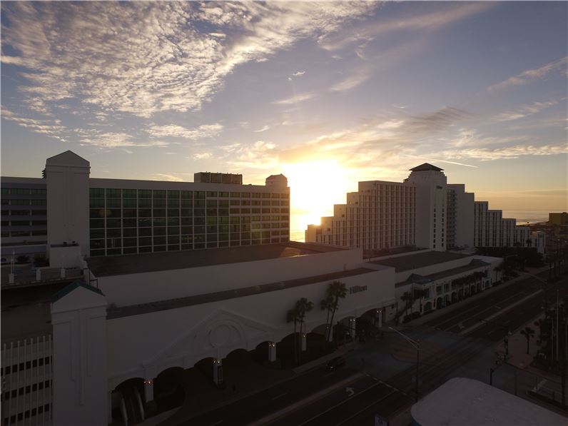 Sunset over the Hilton Daytona Beach Oceanfront Resort, showing the hotel's towering silhouette against a cloudy sky, ideal for Daytona Beach luxury accommodation seekers.