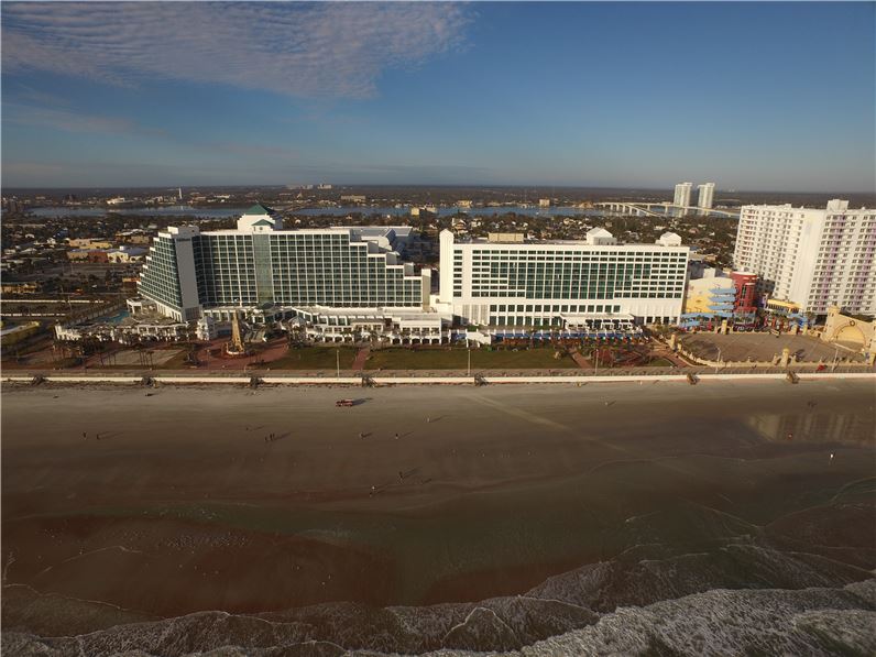 Aerial view of Hilton Daytona Beach Oceanfront Resort located at 100 North Atlantic Avenue, showing the hotel's proximity to the beach and other Daytona Beach hotels, ideal for Daytona 500 accommodations.