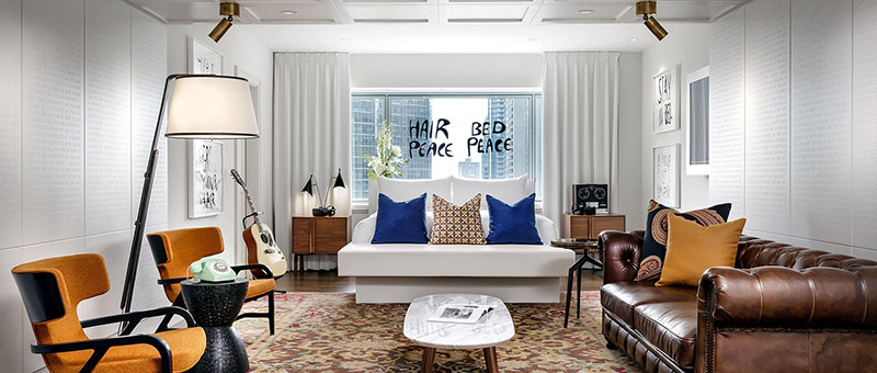 Luxurious hotel room with stylish modern furniture and 'Hair Bed Peace' written on the window, reflecting the premium hospitality at Ritz-Carlton and Fairmont Montreal, ideal for Canadian Grand Prix travel packages.