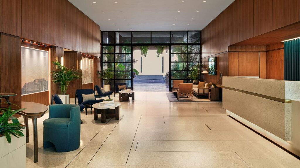 Modern lobby of Thompson Hollywood by Hyatt in Los Angeles, featuring stylish seating areas, wooden panels, and a clear view to the exterior; ideal for Summer Games accommodations.