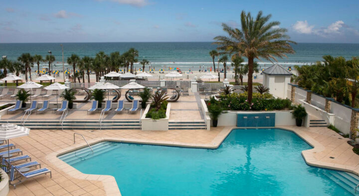 Luxury hotel in Daytona Beach offers poolside relaxation leading to a sandy beach, ideal for accommodations near the Daytona 500 event.