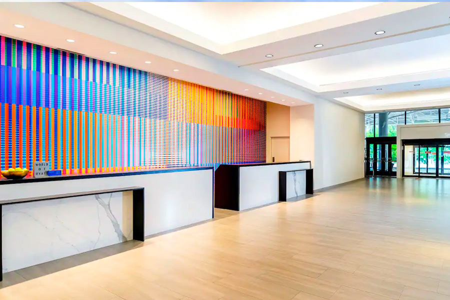 Spacious and modern lobby at the Hyatt Regency Miami, featuring a colorful wall art installation and sleek reception desks, ideal for guests visiting for the Miami Grand Prix.