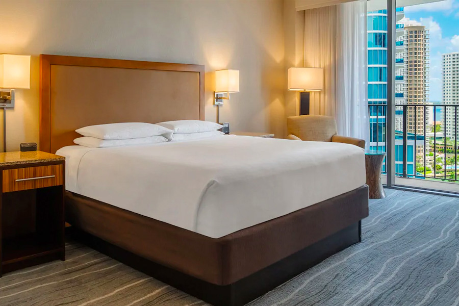 Modern hotel room at Hyatt Regency Miami featuring a large bed, elegant furniture, and a view of downtown, ideal for guests visiting for the Miami Grand Prix.