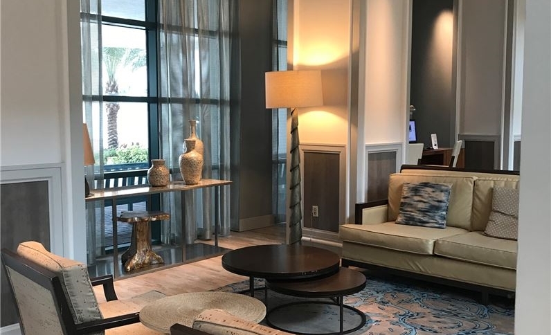 Luxurious seating area in the Hilton Daytona Beach Oceanfront Resort, showcasing elegant furniture and decor with views of palm trees through large glass windows, ideal for Daytona Beach hotel guests.