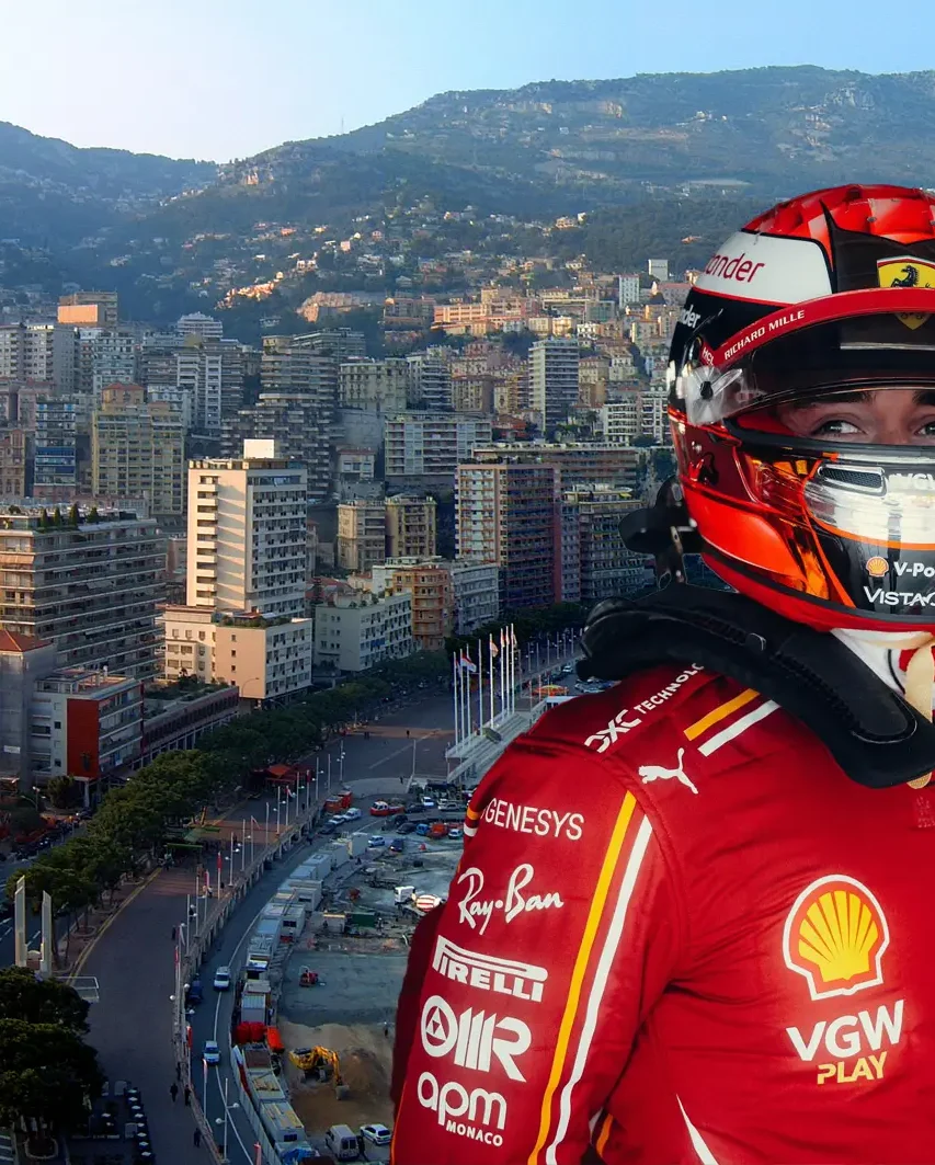 Race car driver in a red racing suit looks out towards the scenic Monaco harbor and cityscape, highlighting the luxury and excitement of the Monaco Grand Prix Packages.