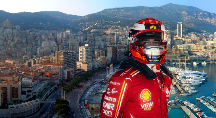 Race car driver in a red racing suit looks out towards the scenic Monaco harbor and cityscape, highlighting the luxury and excitement of the Monaco Grand Prix Packages.