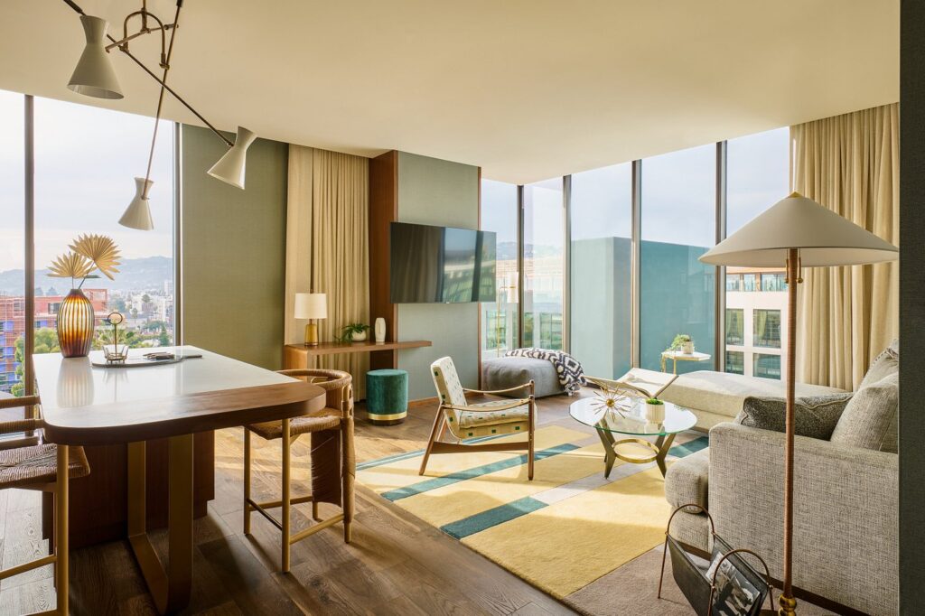 Modern hotel suite at Thompson Hollywood by Hyatt, featuring stylish furnishings and panoramic windows with a view of Los Angeles, ideal for visitors to the Summer Games.