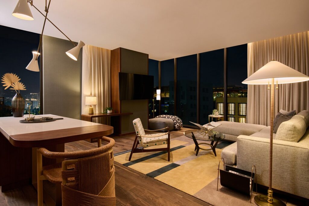 Luxurious hotel room at Thompson Hollywood by Hyatt, featuring a cozy sitting area and modern dining space, ideal for visitors during the Summer Games in Los Angeles.