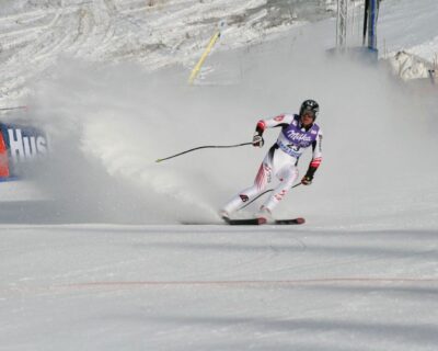 A skier competes in a downhill race, carving through snow with speed, showcasing athleticism at a winter sports event likely to appear in luxury travel guides for sports enthusiasts.