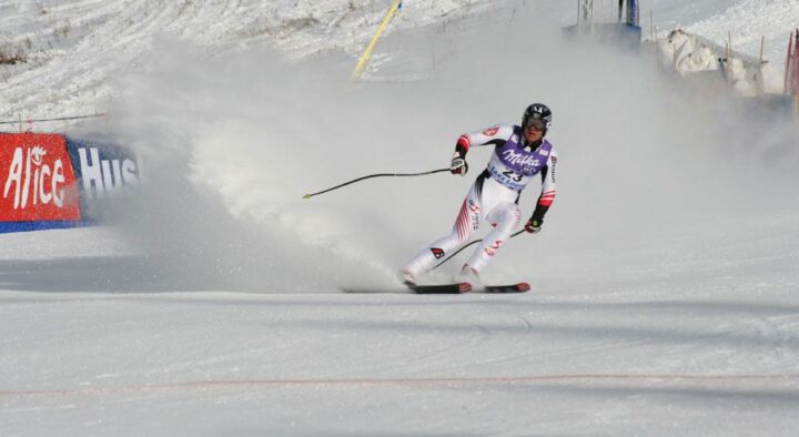 A skier competes in a downhill race, carving through snow with speed, showcasing athleticism at a winter sports event likely to appear in luxury travel guides for sports enthusiasts.